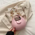 Bolso de hombro rosa tipo media luna con cadena dorada sobre un blazer beige - Rosa