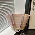 Gestreifte Strohtasche mit rosa und grünen Webmustern und lila Stoffgriffen für den Sommer - Rosa