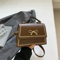 Bolso cuadrado marrón con detalle de lazo dorado y asa superior para mujer - Marrón