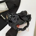 Sac à bandoulière noir avec grand nœud et chaîne dorée dans une pose élégante - Noir