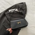 Classic black rectangular shoulder bag with elegant golden bow buckle and slim leather strap - Black