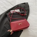 Chic red faux leather underarm bag featuring a gold bow buckle and slim shoulder strap - Red