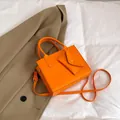 Schicke orangefarbene Umhängetasche aus Kunstleder mit passender Geldbörse und Goldakzenten - Orange