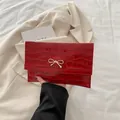 Minimalist red crocodile embossed envelope bag with a golden metal bow decoration - Red