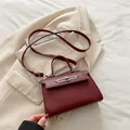 Elegante borsa Kelly rosso intenso con fibbia in metallo argento su blazer beige - Rosso