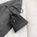 Klassische schwarze Kelly-Tasche mit Lederschleife und goldenen Metallteilen - Schwarz