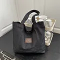 Grande borsa tote in denim nero con etichetta in pelle marrone e ampi spallacci - Nero