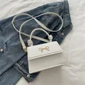 Mini bolso blanco de cuero PU con lazo dorado sobre fondo de chaqueta vaquera azul - Blanco