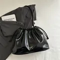 Fashionable black drawstring bucket bag with shiny finish and silver bow detail - Black