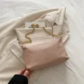 Pink woven baguette bucket bag with gold chain strap on a beige blazer background - Pink