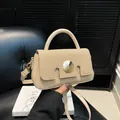 Chic beige crossbody bag with woven flap and gold buckle shown against dark background - Khaki