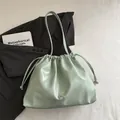 Light green glossy leather drawstring bucket bag with decorative metallic bow detail - Green