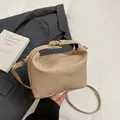 Bolso tipo almohada beige con textura tejida y broche dorado para un look chic - Caqui