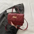 Bolso acolchado rojo oscuro con hebilla en H dorada sobre una chaqueta gris - Rojo