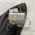 Bolso bandolera plateado acolchado con cierre en H dorado sobre un fondo moderno - Plateado
