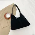 Black suede hobo bag with gold metal rivets and a leather shoulder strap on white fabric - Black