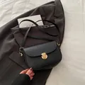 Bolso de hombro negro de cuero granulado con hebilla dorada sobre americana gris - Negro