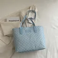 Sac cabas bleu clair avec motif M et logo Fashion posé sur un blazer crème - Bleu