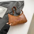 Braune Retro-Schultertasche mit Fashion-Prägung auf grauem strukturiertem Anzughintergrund - Braun
