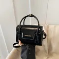 Bolso de mano cuadrado pequeño en charol negro brillante con asa y letras doradas - Negro
