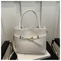 White woven bucket bag with gold hardware buckle and round top handles for daily commute - White