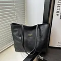 Elegant black leather tote bag with embossed floral texture and gold logo hardware - Black