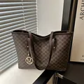 Sac cabas marron avec monogramme M et breloque ronde dans un décor de fenêtre épuré - Marron