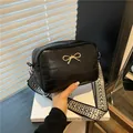 Minimalist black square shoulder bag with golden bow and ethnic woven strap - Black