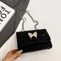 Black textured shoulder bag with silver bow accent and fine metal chain strap - Black