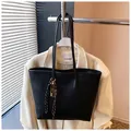 Dettaglio borsa tote in PU nero grana litchi con pendente a chiave in metallo e racchetta - Nero