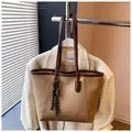 Dettaglio della borsa tote in pelle PU color albicocca con logo dorato e foulard a righe - Kaki