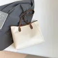 Bolso tote minimalista en contraste crema y marrón con elegantes anillos de metal dorado - Blanco Roto