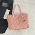 Borsa tote rosa con monogramma e ciondolo a M dorato su lenzuola bianche chic - Rosa