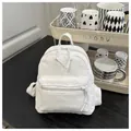 Detalle de textura de la mini mochila de pana color crema en mesa de madera - Blanco