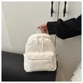 Detailed view of cream corduroy backpack texture and zipper pocket on the front - White