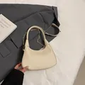 Chic cream textured hobo bag with gold chain strap on grey blazer background - Beige