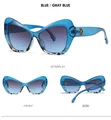 Detailweergaven van blauwe cat-eye zonnebril met marmerpatroon en gouden logo-accent - Blauw Frame Grijsblauwe Lenzen