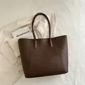 Dark brown lychee leather tote bag with double straps on textured white fabric - Brown