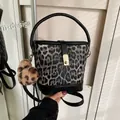 Fashionable leopard print bucket bag with black leather trim and golden metal lock - With Pendant / Black