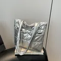 Silver quilted puffer tote bag with metallic finish and top handle on display - Silver