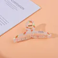 Macro detail of large acrylic hair claw with red strawberry prints and pearl finish - Carrot / Large