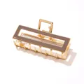 Detail of a rectangular gold metal hair claw clip with a glossy brown acetate inlay finish - Coffee