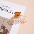 Macro shot of an amber gradient hair claw clip with a polished finish on a magazine page - Orange