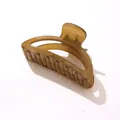 Primer plano de una pinza para el pelo ámbar con un mecanismo de resorte metálico fuerte - Marrón