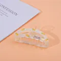 Detailed view of a transparent hair claw clip featuring yellow pineapple patterns - Pineapple