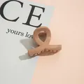 Draufsicht einer glänzenden khakifarbenen Haarklammer mit gedrehtem Design auf Karte - Beige Kaffee