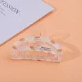Detailed close-up of transparent acrylic hair claw clip with pink strawberry pattern - Carrot