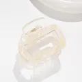 Macro shot of square hair claw clip featuring yellow cream marble pattern and metal spring - Yellow