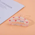 Detail of translucent strawberry hair claw clip with colorful finish on pink background - Strawberry