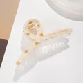 Dettaglio laterale della pinza per capelli beige a pois con molla dorata e logo - Lettera A